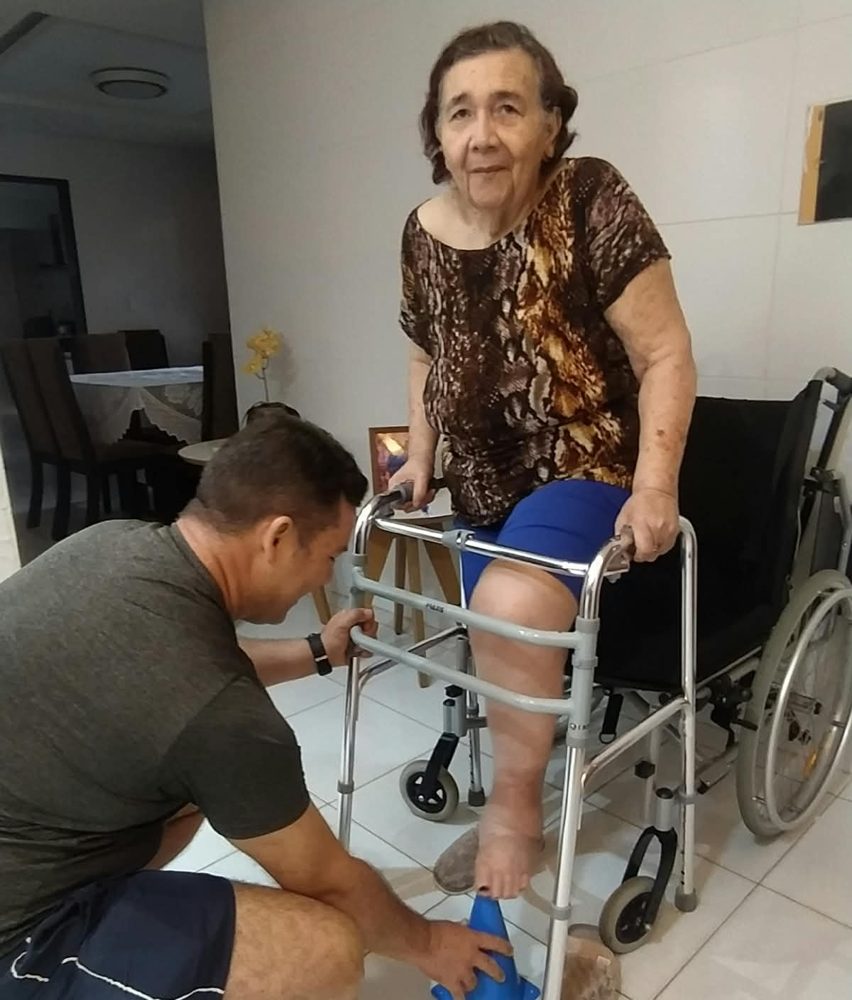 Antônio auxiliando aluna com andador em atendimento domiciliar