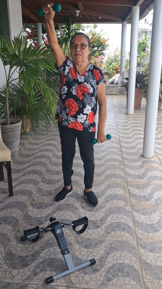 Aluna treinando com halteres na varanda
